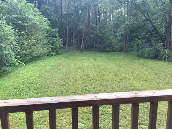 View from porch deck of yard & treed acreage with walking trail